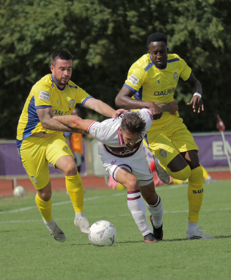 Football player driving forward between two defenders